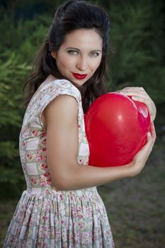 Valentine's Day. Beautiful smiling woman with a gift in the form of heart in his hands, garden background