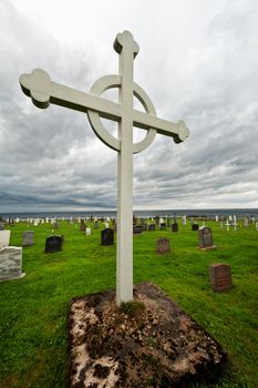 Cross above a graveyard under storm clouds