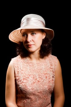 An attractive woman in a hat on a black background. portrait