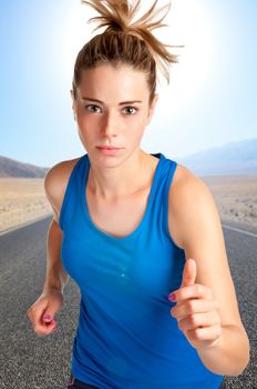 Young fit woman jogging,with a road behind and mountains