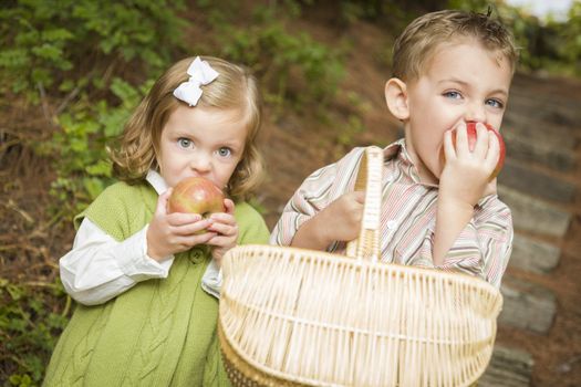 Two Adorable Children Eating Delicious Red Apples Outside.