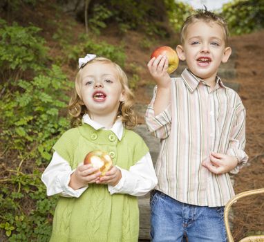 Two Adorable Children Eating Delicious Red Apples Outside.