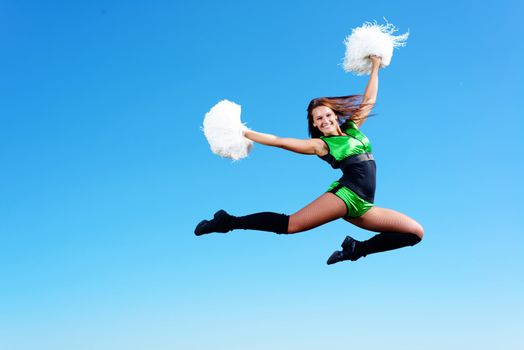 cheerleader girl jumping on a background of blue sky