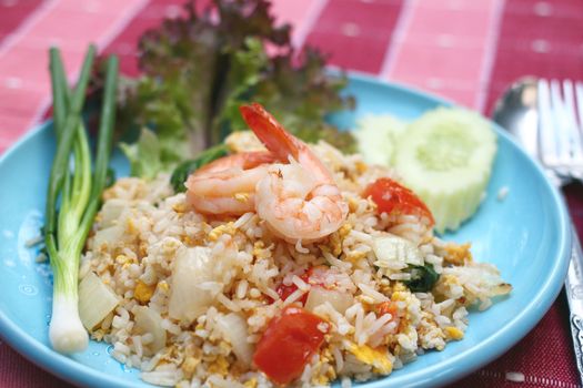 Shrimp fried rice with eggs, onion and tomato on blue plate