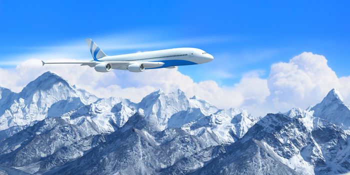 White passenger plane flying in the blue sky above the mountains with snow tops