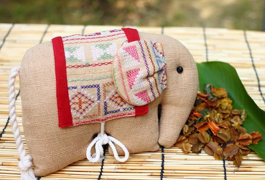 Herb package in a form of elephant with thai cloth, put on table cloth made from wooden