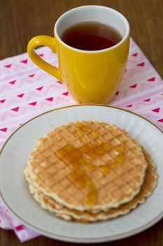 Round wafers, yellow cup of tea on a napkin