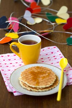 Round wafers, yellow cup with a long spoon on a napkin, with a heart of paper in the background