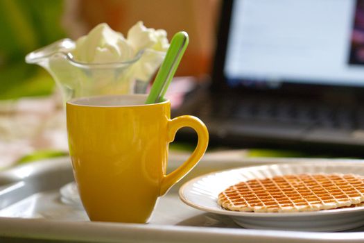 Round wafers and tea, breakfast on the background of laptop