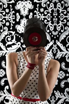 young woman looking through the hole of a small record with a red label