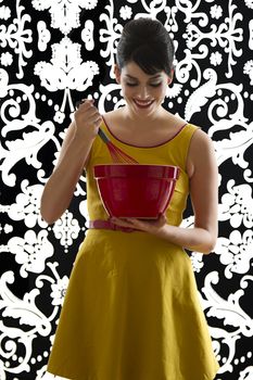 young woman in front of a black and white textured background with 60's inspired style, holding a red whisk in a red bowl