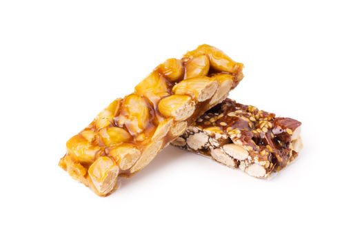 Two honey bars with peanuts and sesame seeds on white background