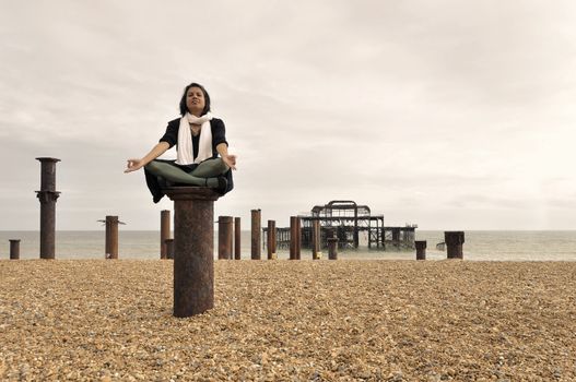 Young Asian woman meditating next to the West Pier in Brighton, England, UK