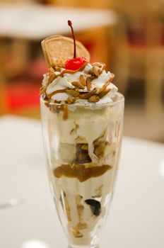 Vanilla ice cream in bowl with almond  , caramel sauce and cherry ,