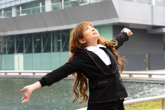 Woman relaxing with arms open enjoying her freedom and office building background