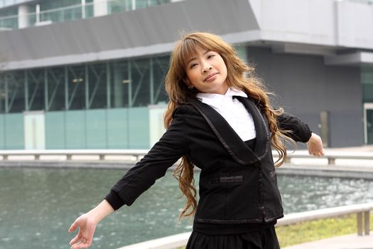 Woman relaxing with arms open enjoying her freedom and office building background