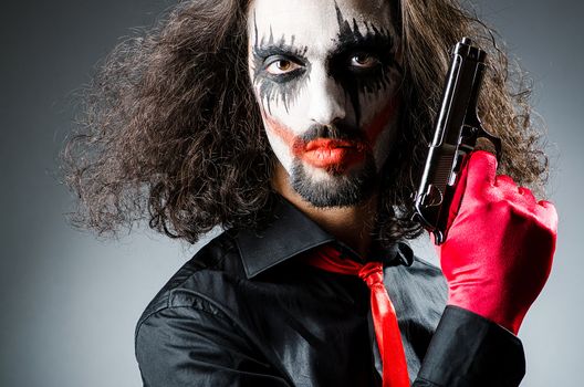 Evil clown with gun in dark room