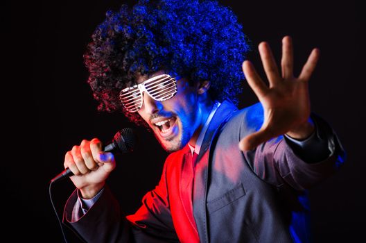 Young singer in afro wig singing at disco