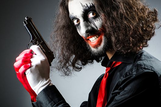 Evil clown with gun in dark room