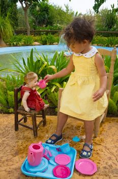 Small girl playing tea time with her vintage doll