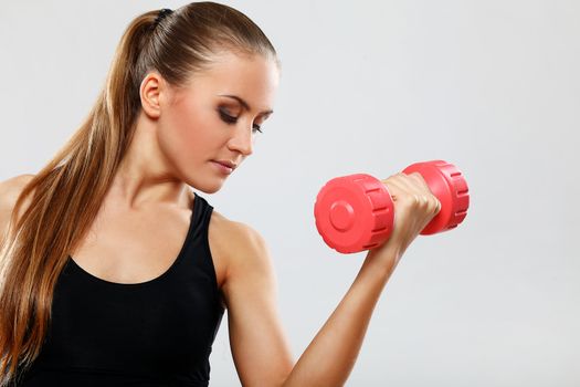 Beautiful brunette working out with dumbbells over gray background