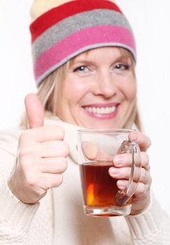 Mid age Woman With Hot tea Wearing Winter Clothes showing thumbs up on a white background