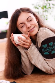 Close up of cute and attractive young woman have a warm from cup of tea at home