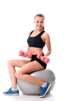 Beautiful and smiling woman doing exercises with dumbells on fitness ball over white background