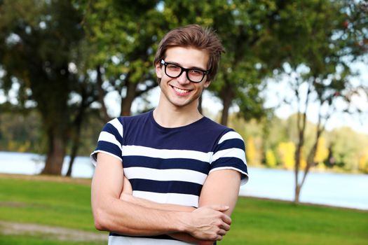 Portrait of young and smiling cute man with glasses in park