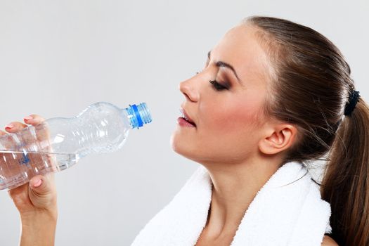 Fitness woman drink water after train on grey background