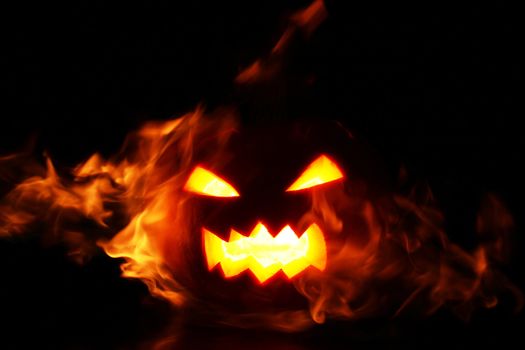 halloween pumpkin in fire over a black background