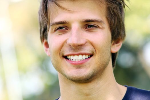 Portrait of young and smiling cute man in park