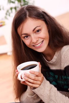 Close up of cute and attractive young woman have a warm from cup of tea at home