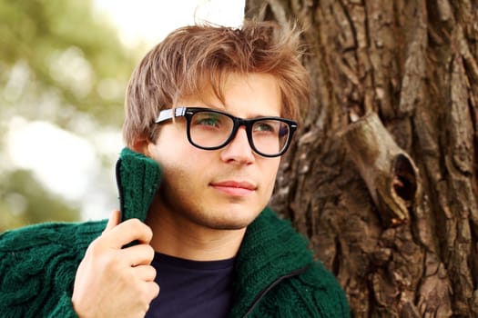 Potrait of handsome and smart guy at cold autumn day in the park