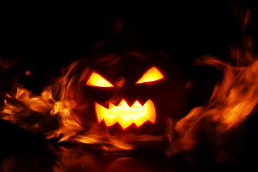 halloween pumpkin in fire over a black background