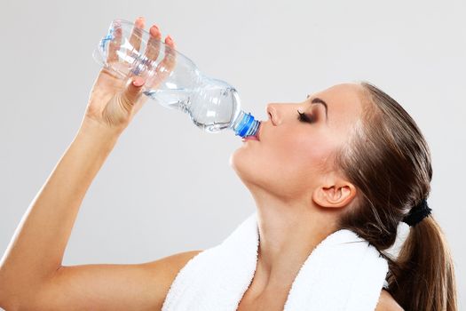 Fitness woman drink water after train on grey background