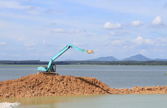 Excavator located by a river and ready for work