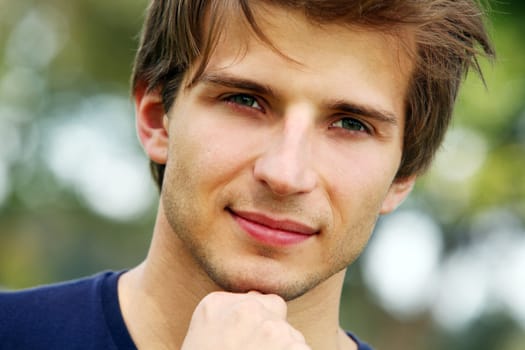 Portrait of young and smiling cute man in park