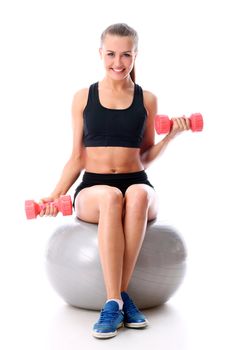 Beautiful and smiling woman doing exercises with dumbells on fitness ball over white background