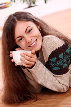 Close up of cute and attractive young woman have a warm from cup of tea at home