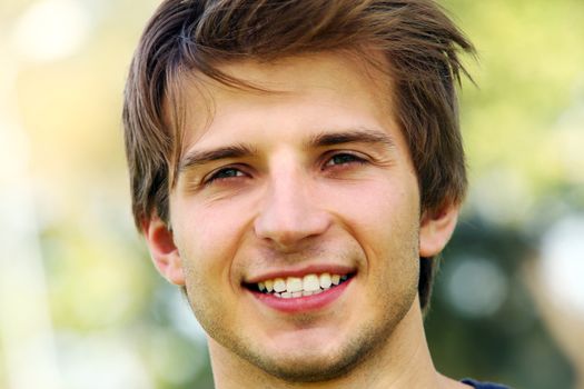 Portrait of young and smiling cute man in park