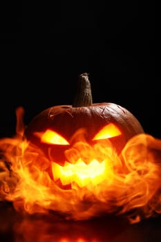 halloween pumpkin in fire over a black background