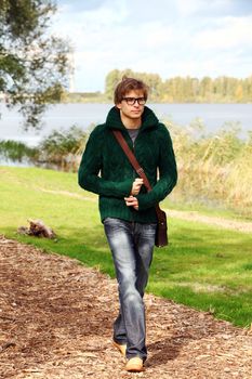 Cute and smart guy walking at cold autumn day in sunny park