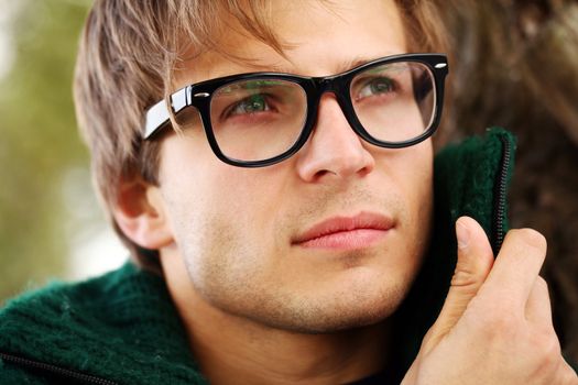 Potrait of handsome and smart guy at cold autumn day in the park