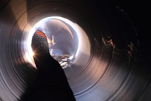 Male welder worker wearing protective clothing fixing welding   and sewerage plumbing pipeline outside on site