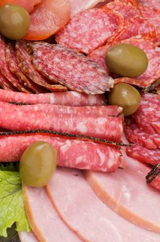 Background of Delicatessen Meat with Salami, Baloney, Pepperoni and Green Olives closeup
