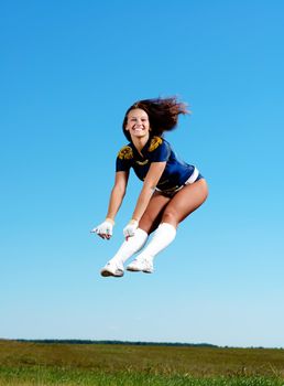 cheerleader girl jumping on a background of blue sky