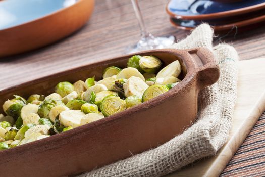 Roasted parsnips and brussel sprouts in terracotta baking dish.