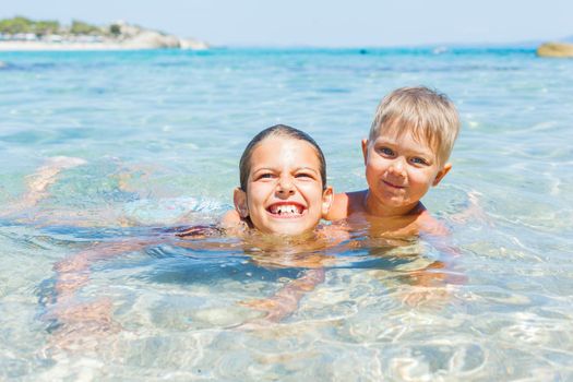 Happy kids. Sister and brother playing and swimming in the transparent sea