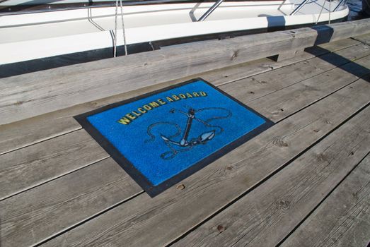 Doormat ahead of a boat that is moored to the pier in Halden and welcomes you aboard.